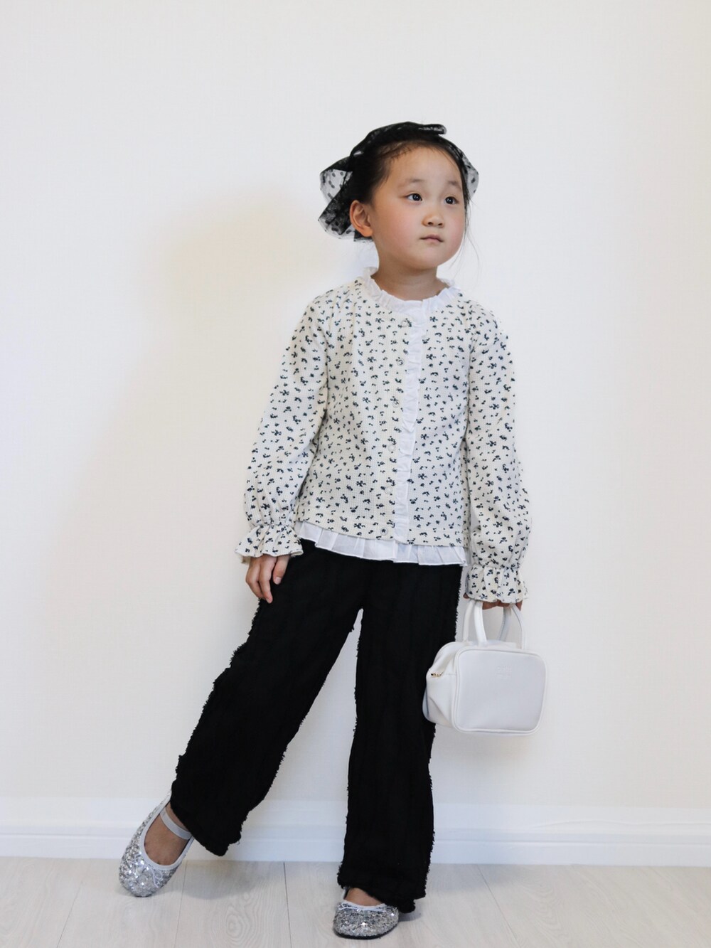 ホワイト系のカーディガン/ボレロ、シルバー系のバレエシューズ、ブラック系のその他パンツを着用したキッズの秋コーディネートの2枚目の写真