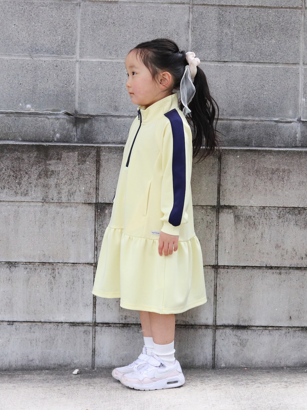 イエロー系のワンピース、ピンク系のスニーカー、ホワイト系のソックス/靴下を着用したキッズの冬コーディネートの3枚目の写真