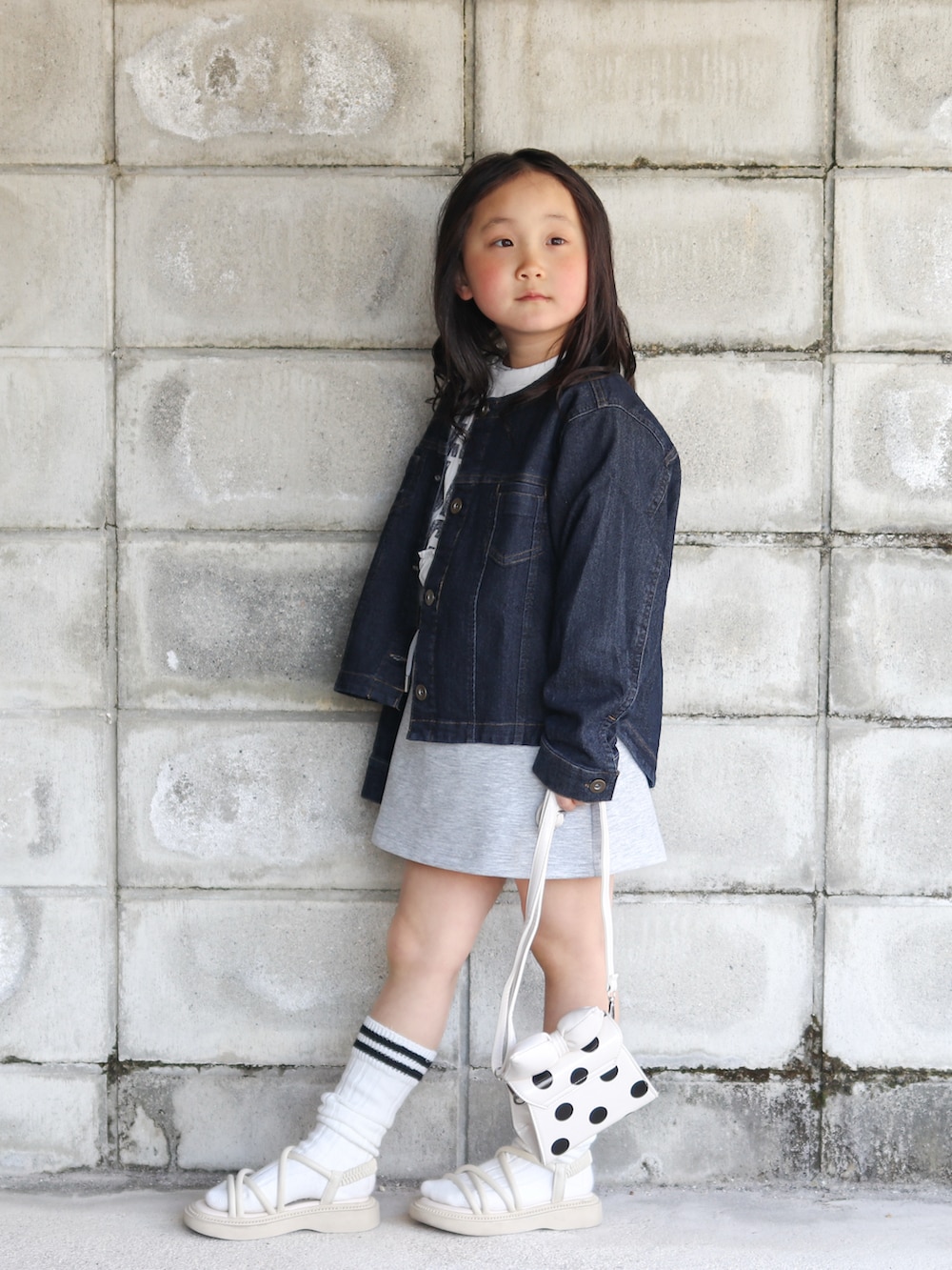 ブルー系のブルゾン、ホワイト系のワンピース、ホワイト系のショルダーバッグを着用したキッズの春コーディネートの3枚目の写真