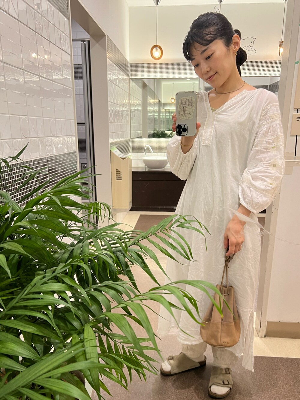 ホワイト系のワンピース、ベージュ系のサンダル、ゴールド系のピアス（両耳用）を着用したレディースの夏コーディネートの2枚目の写真