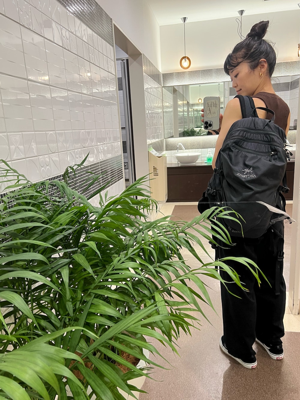 ブラウン系のタンクトップ、ブラック系のバックパック/リュック、ブラック系のスニーカーを着用したレディースの夏コーディネートの2枚目の写真