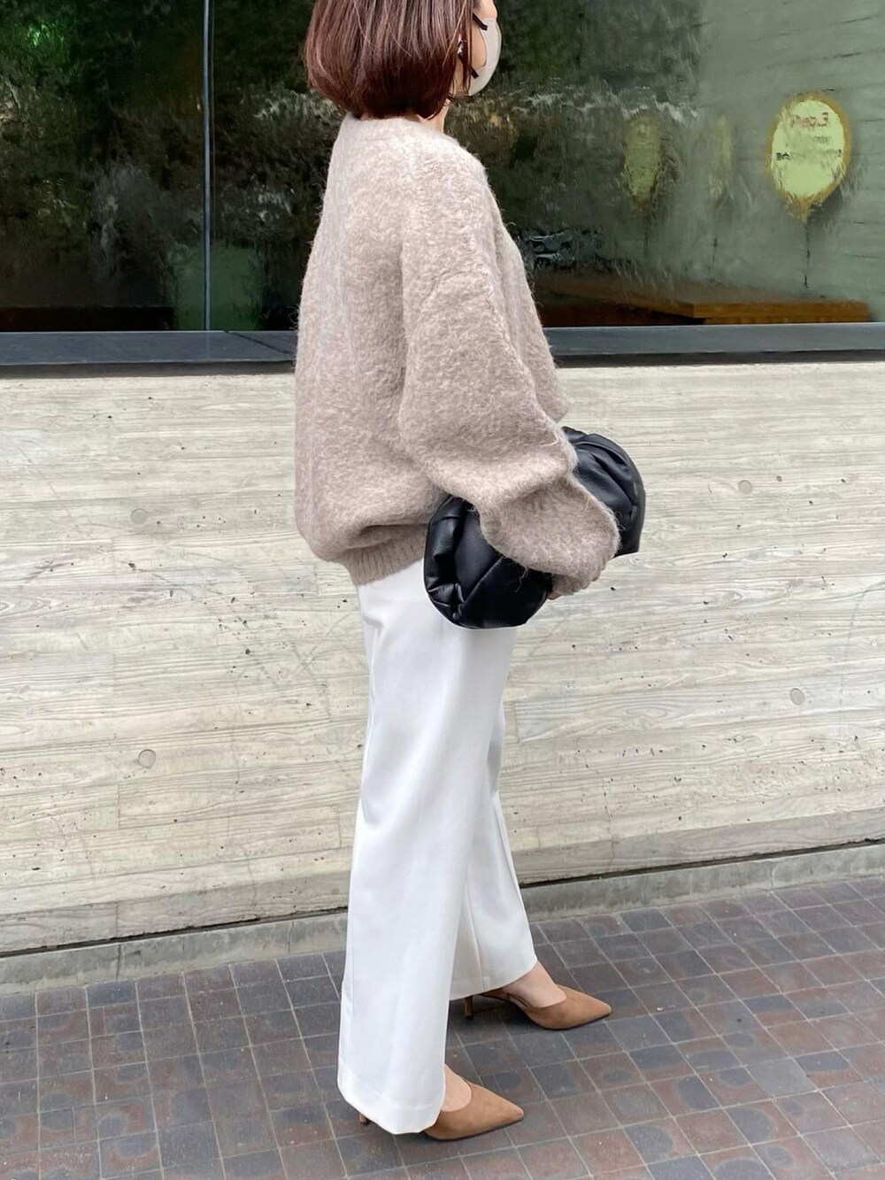 ホワイト系のパンツ、ブラウン系のニット/セーター、ブラック系のクラッチバッグを着用したレディースの秋コーディネートの2枚目の写真