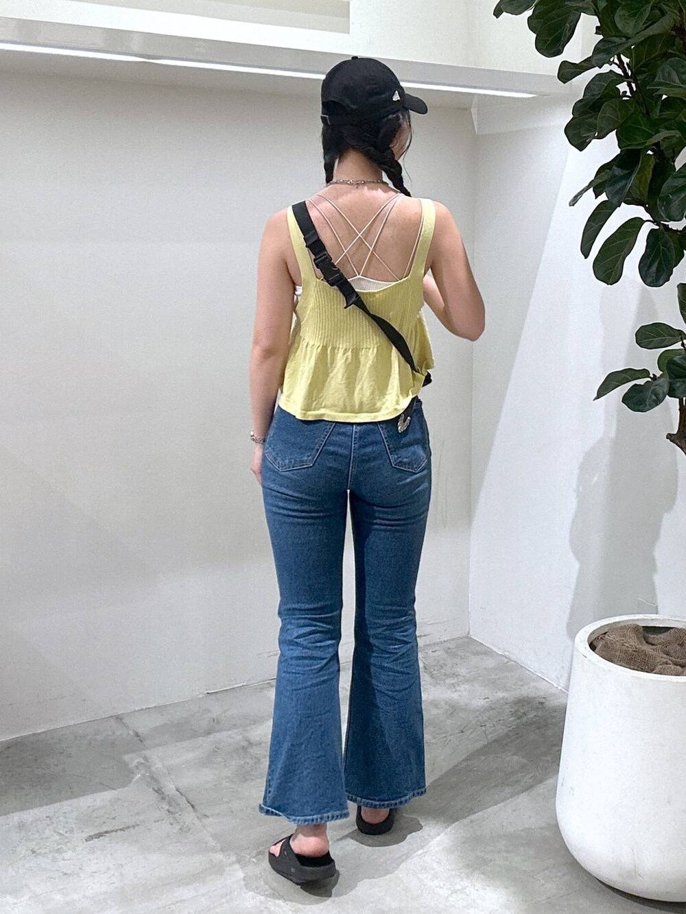 ブラック系のショルダーバッグ、ブラック系のサンダル、ブルー系のデニムパンツを着用したレディースの夏コーディネートの3枚目の写真