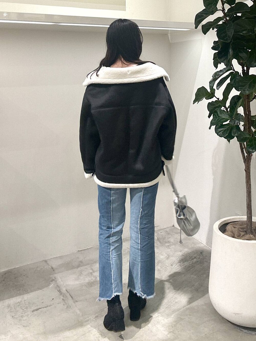 シルバー系のショルダーバッグ、ブラック系のTシャツ/カットソー、ブラック系のムートンコートを着用したレディースの冬コーディネートの4枚目の写真
