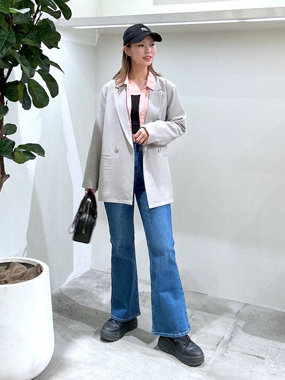 ブラック系のスニーカー、ピンク系のシャツ/ブラウス、ブラック系のショルダーバッグを着用したレディースの春コーディネートの3枚目の写真