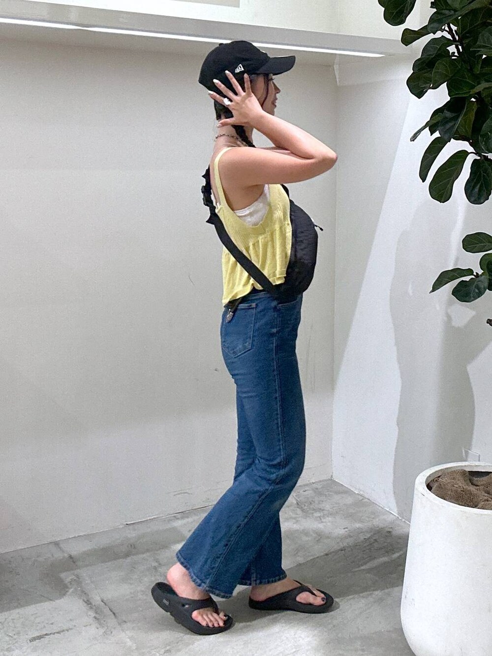 ブラック系のショルダーバッグ、ブラック系のサンダル、ブルー系のデニムパンツを着用したレディースの夏コーディネートの2枚目の写真