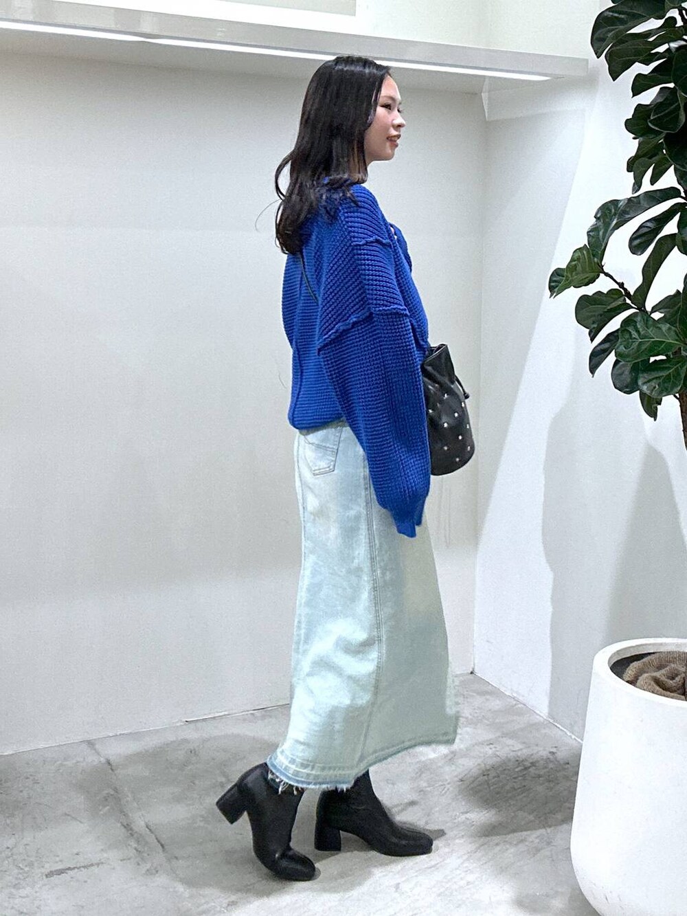 ブルー系のデニムスカート、ブラック系のショルダーバッグ、ブラック系のブーツを着用したレディースの冬コーディネートの3枚目の写真