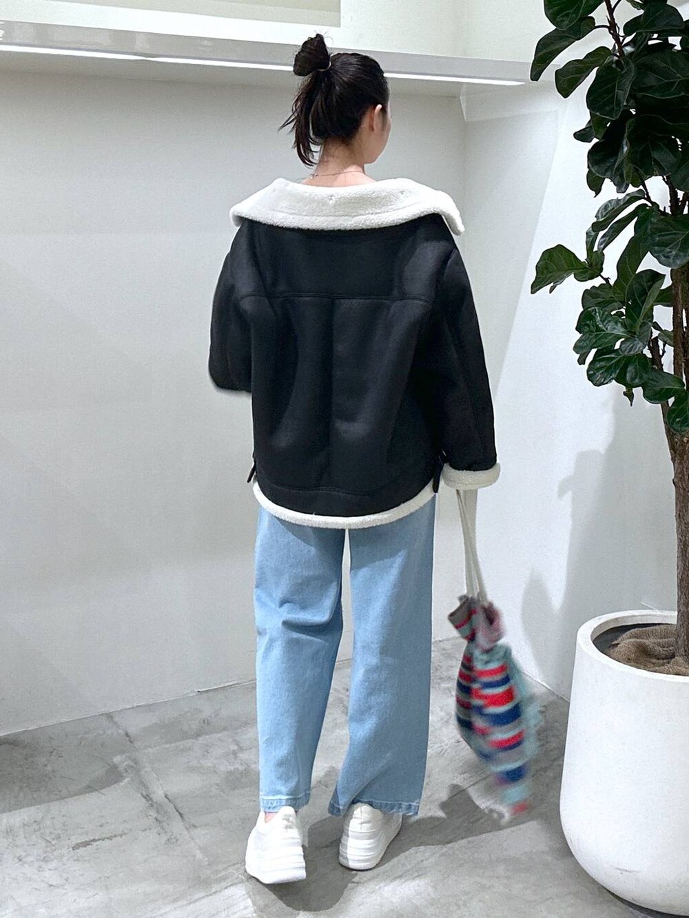 ホワイト系のスニーカー、ホワイト系のTシャツ/カットソー、ブラック系のムートンコートを着用したレディースの冬コーディネートの4枚目の写真