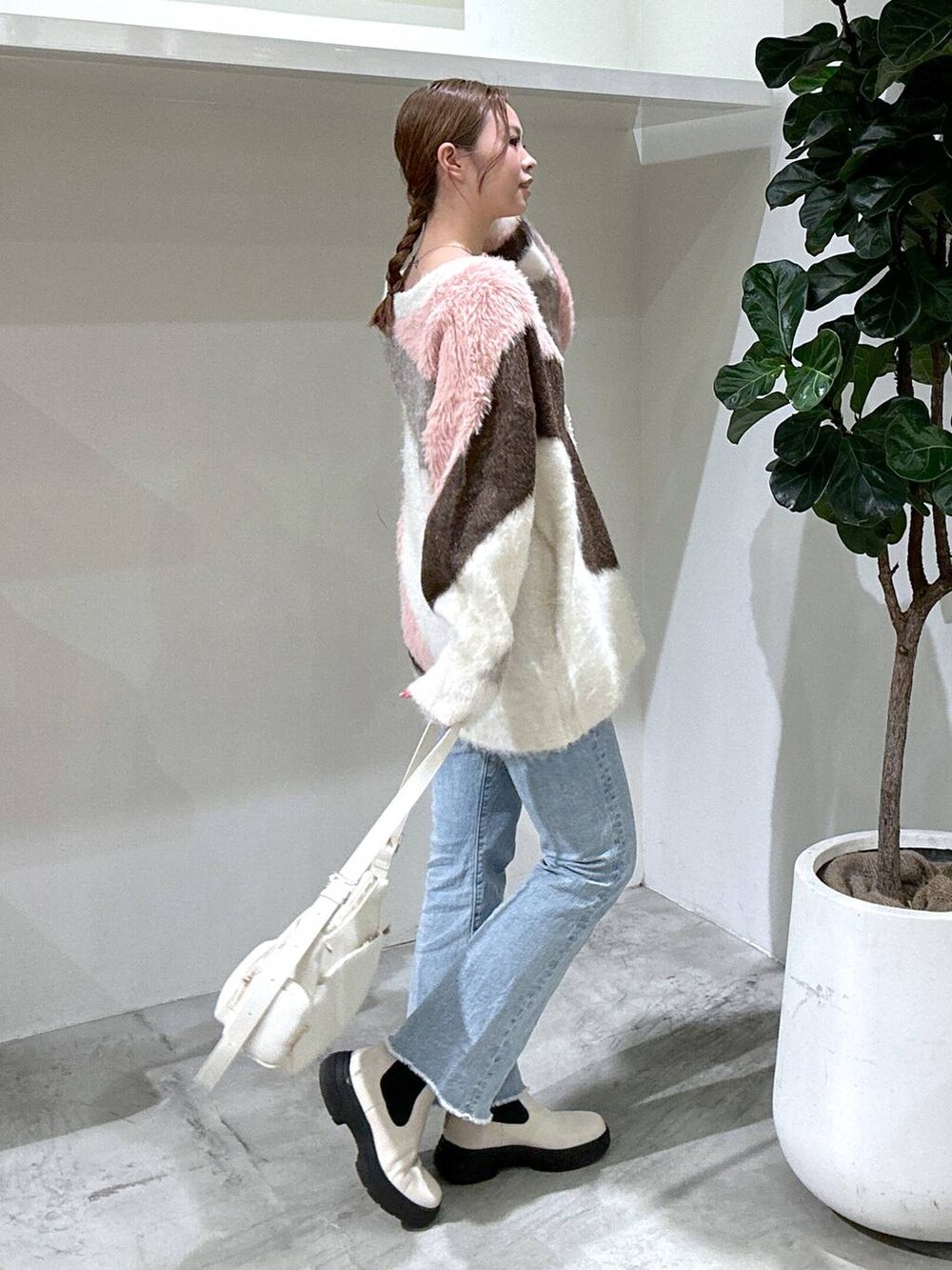 ブルー系のデニムパンツ、ホワイト系のブーツ、ホワイト系のカーディガン/ボレロを着用したレディースの秋コーディネートの2枚目の写真