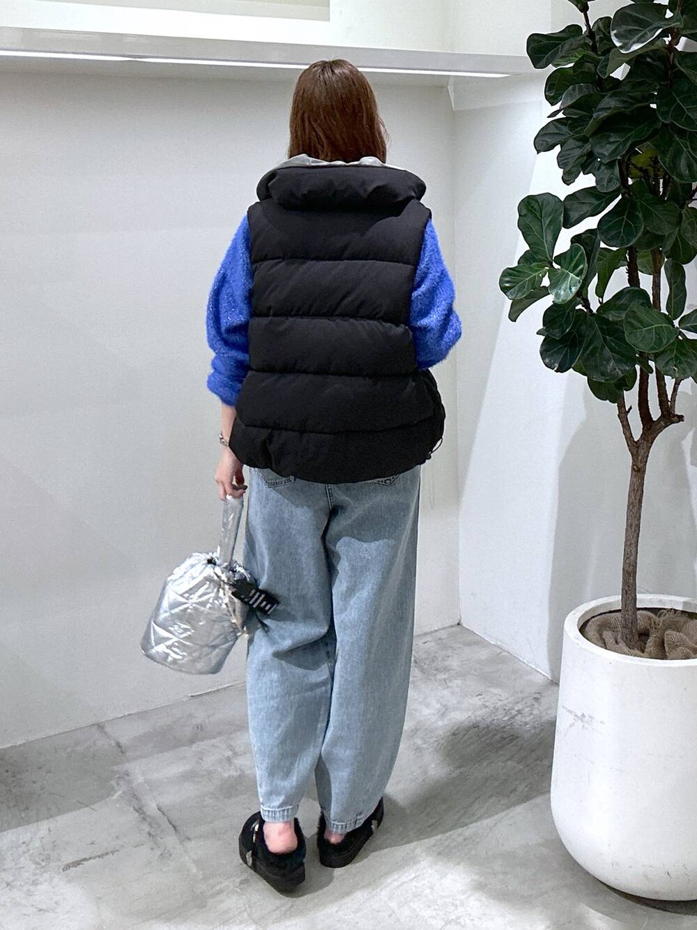 ブラック系のベスト、シルバー系のショルダーバッグ、ブルー系のデニムパンツを着用したレディースの秋コーディネートの3枚目の写真