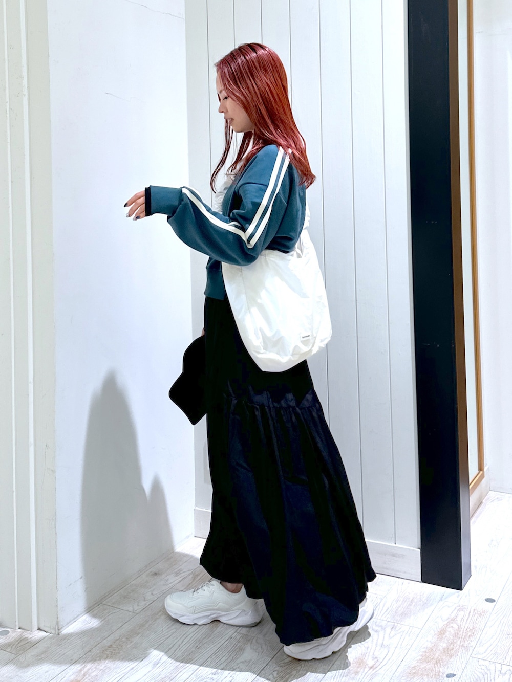 ブラック系のスカート、グリーン系のスウェット、ホワイト系のショルダーバッグを着用したレディースの春コーディネートの4枚目の写真