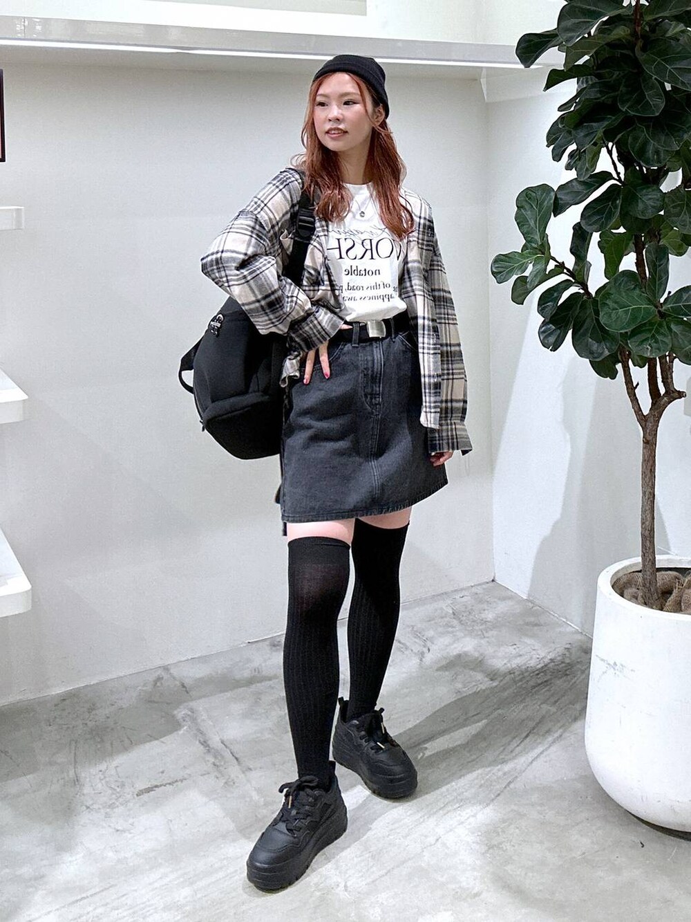 グレー系のスカート、ブラック系のバックパック/リュック、ホワイト系のTシャツ/カットソーを着用したレディースの秋コーディネートの2枚目の写真