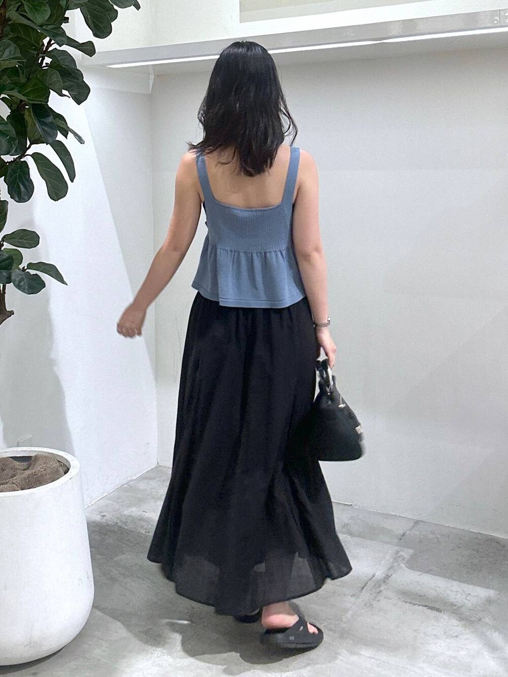 ブラック系のスカート、ブラック系のサンダル、ブルー系のニット/セーターを着用したレディースの夏コーディネートの2枚目の写真