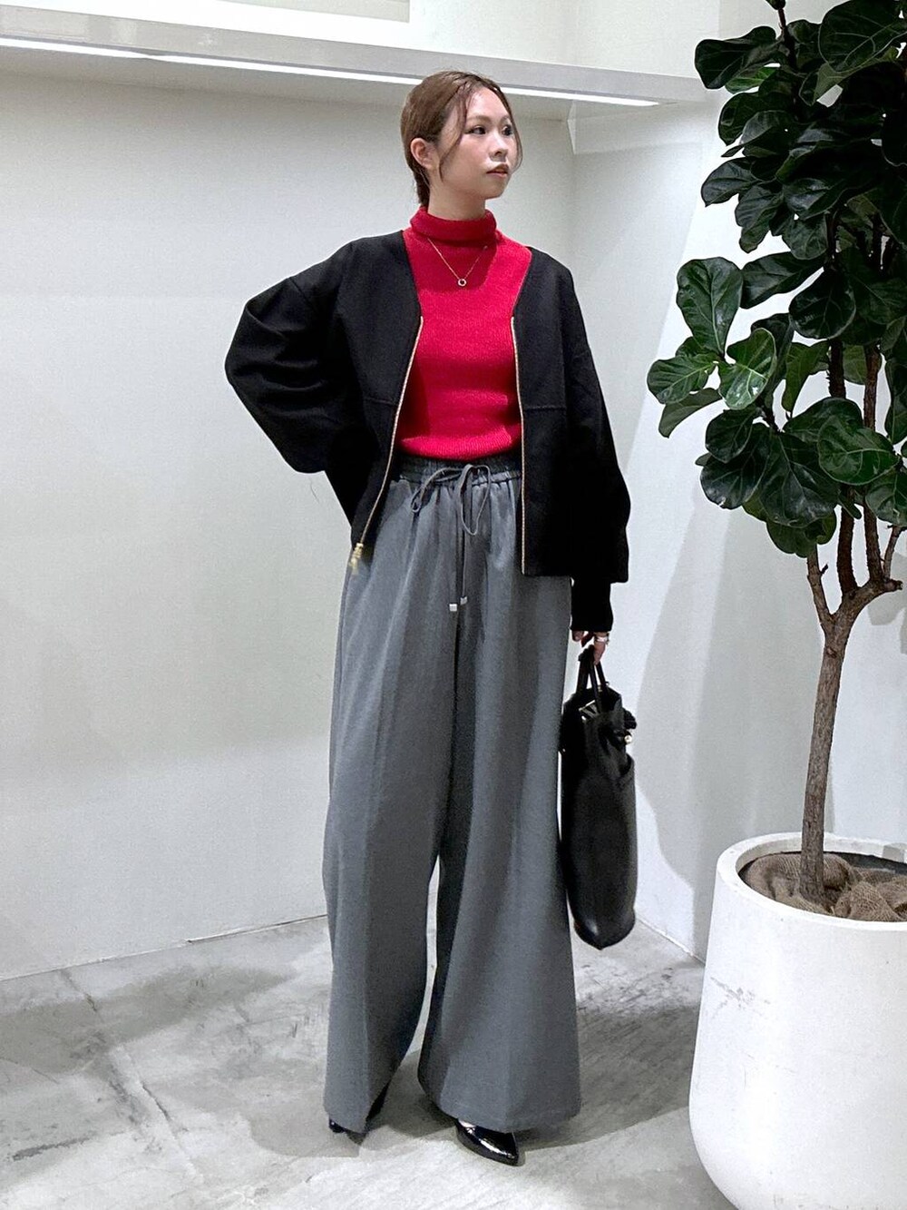 レッド系のニット/セーター、ブラック系のブルゾン、ブラック系のトートバッグを着用したレディースの秋コーディネートの3枚目の写真