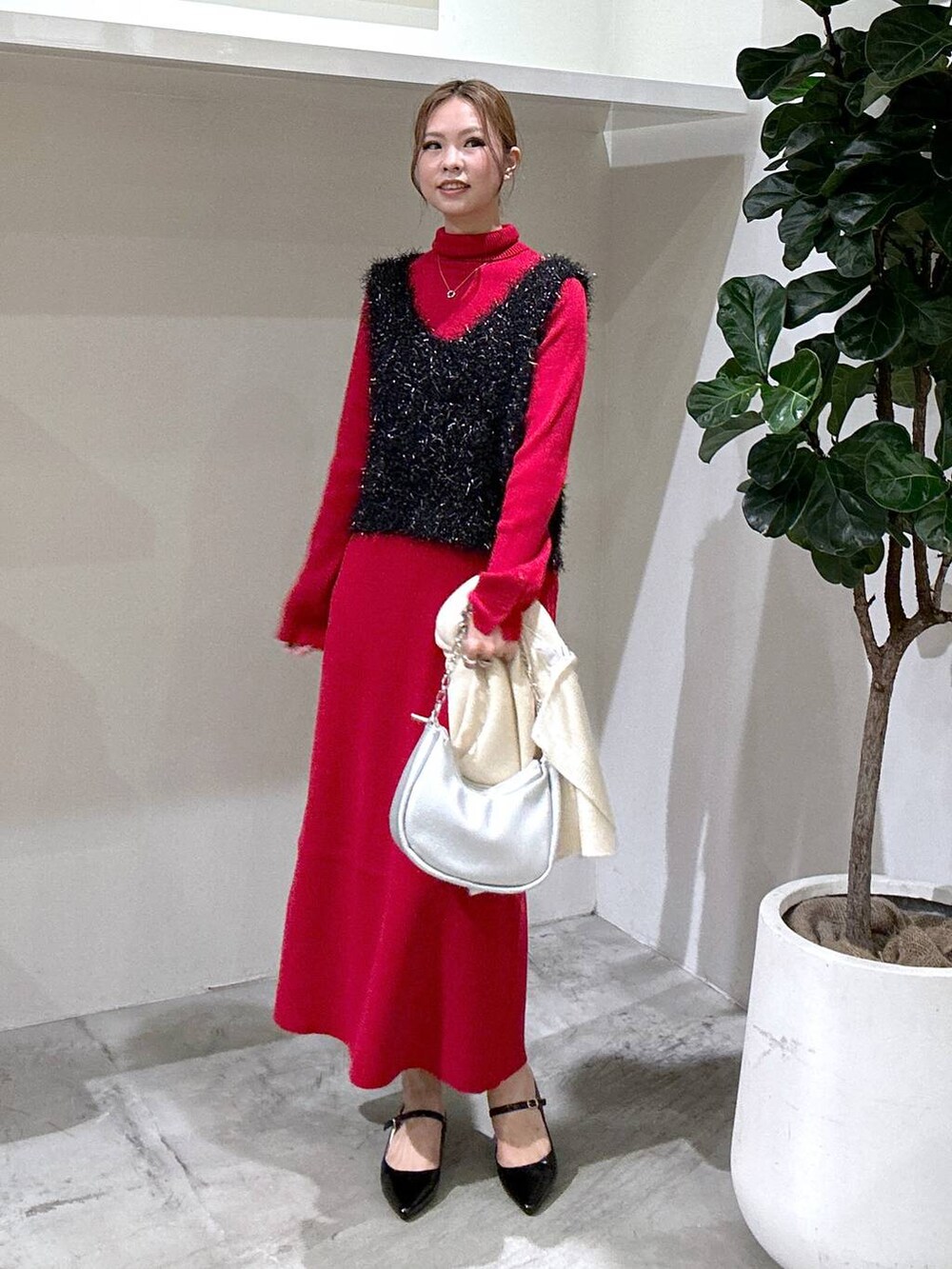 シルバー系のショルダーバッグ、ブラック系のパンプス、レッド系のニット/セーターを着用したレディースの秋コーディネートの2枚目の写真