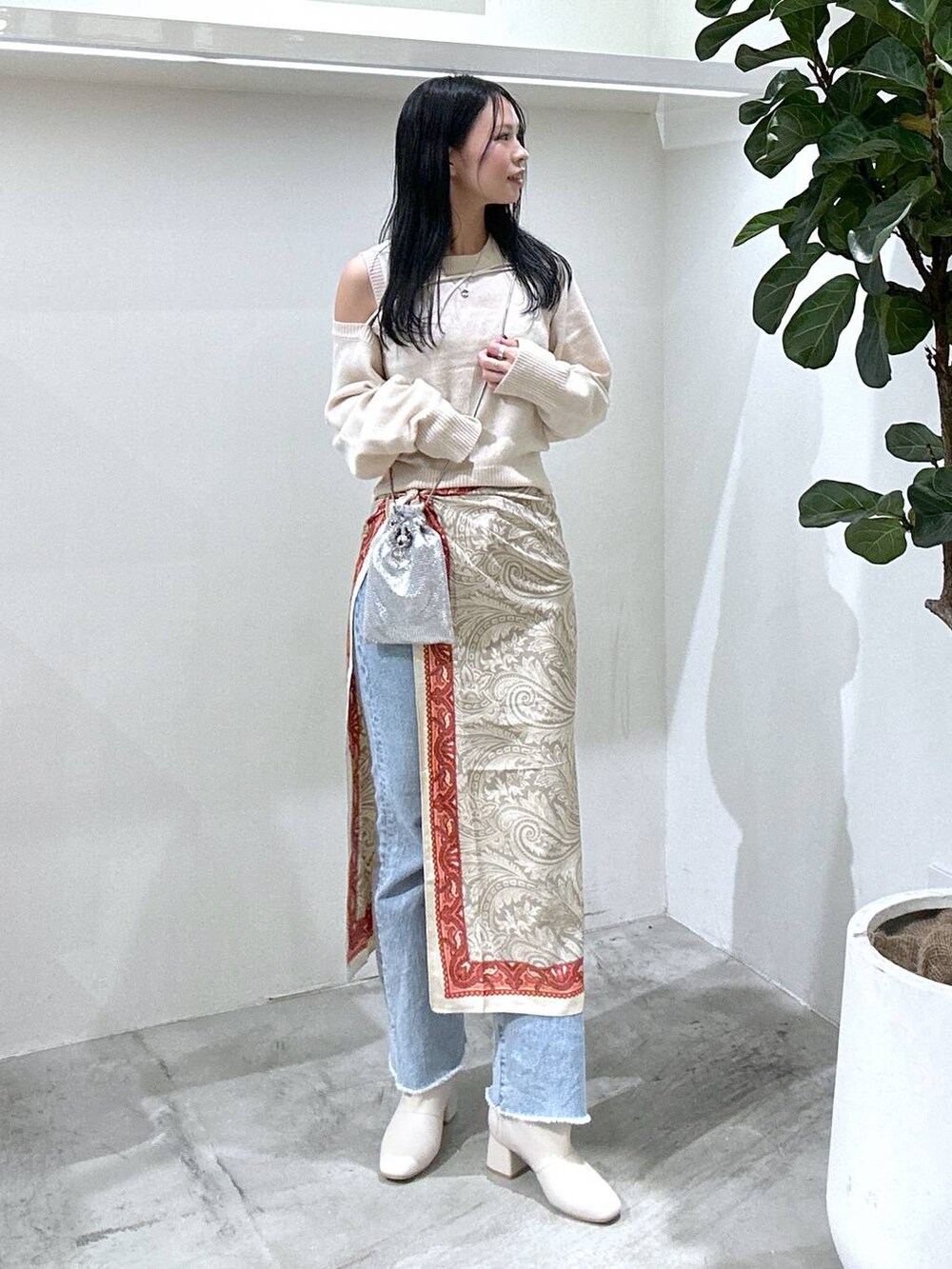 ブルー系のデニムパンツ、ベージュ系のブーツ、ホワイト系のニット/セーターを着用したレディースの冬コーディネートの2枚目の写真