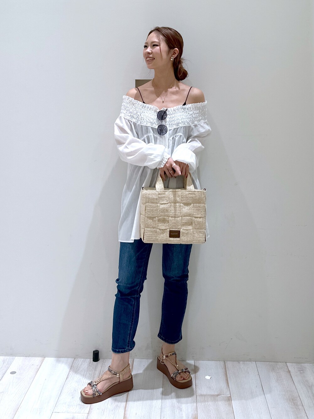 ブラウン系のトートバッグ、ベージュ系のサンダル、ブルー系のデニムパンツを着用したレディースの春コーディネートの2枚目の写真