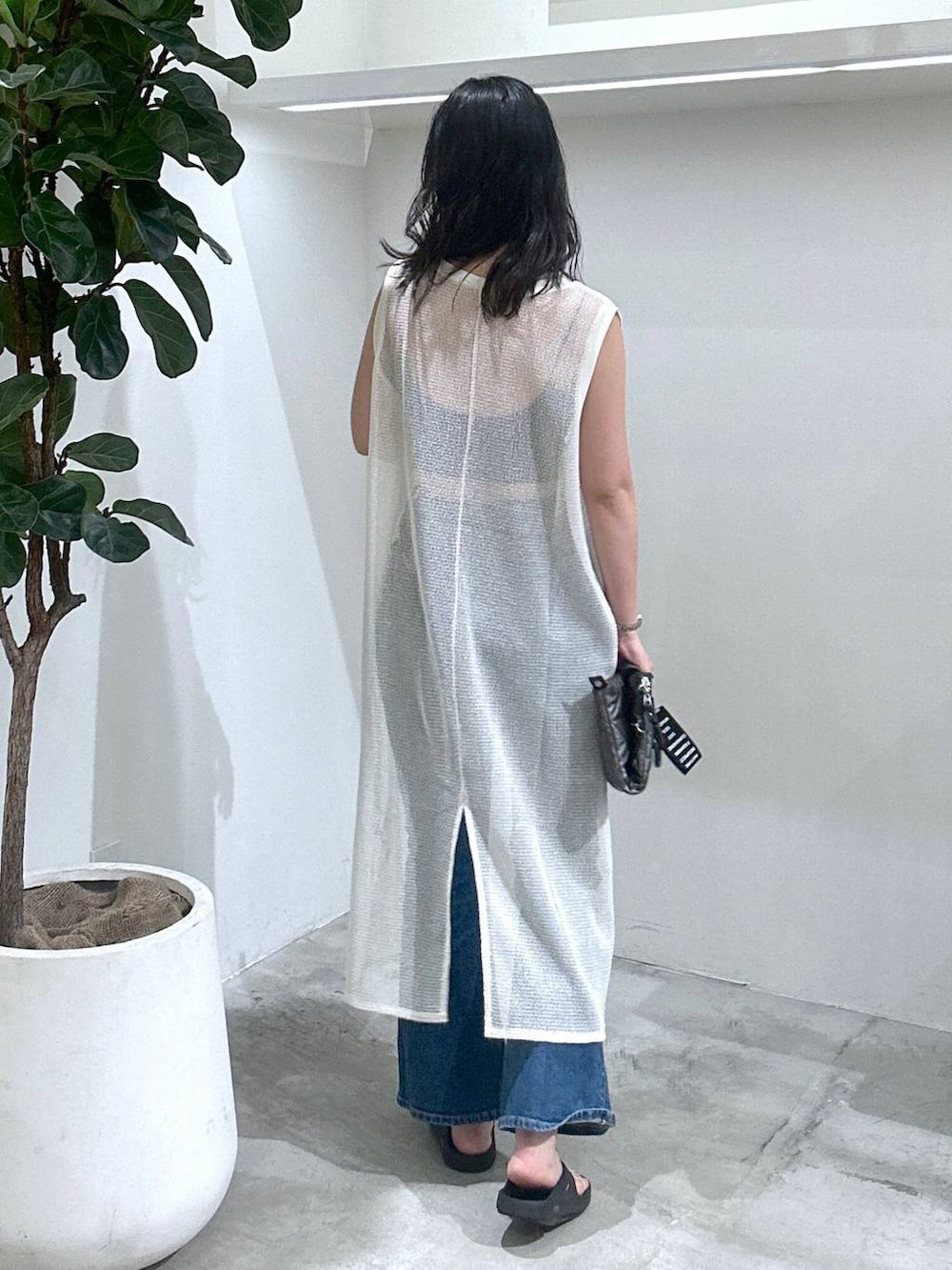 ブルー系のデニムパンツ、ホワイト系のワンピース、ブラック系のトートバッグを着用したレディースの夏コーディネートの3枚目の写真