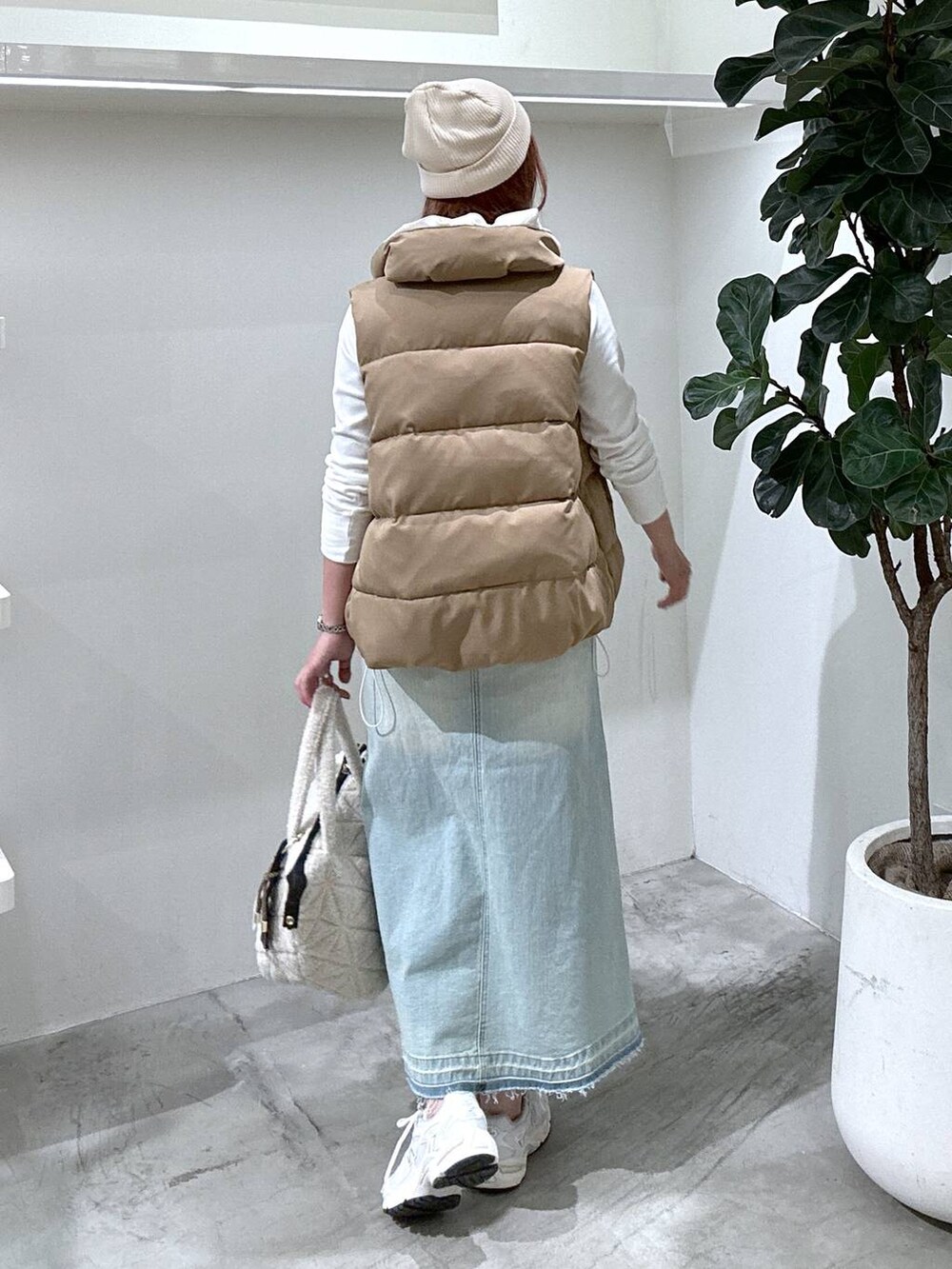 グレー系のスニーカー、ブルー系のデニムスカート、ブラウン系のベストを着用したレディースの秋コーディネートの4枚目の写真