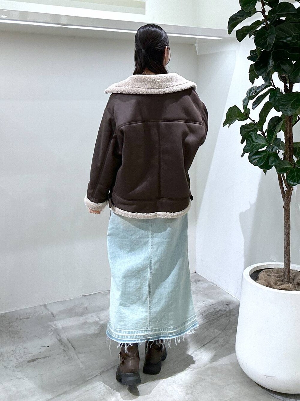 ブルー系のデニムスカート、ブラウン系のブーツ、シルバー系のショルダーバッグを着用したレディースの冬コーディネートの4枚目の写真