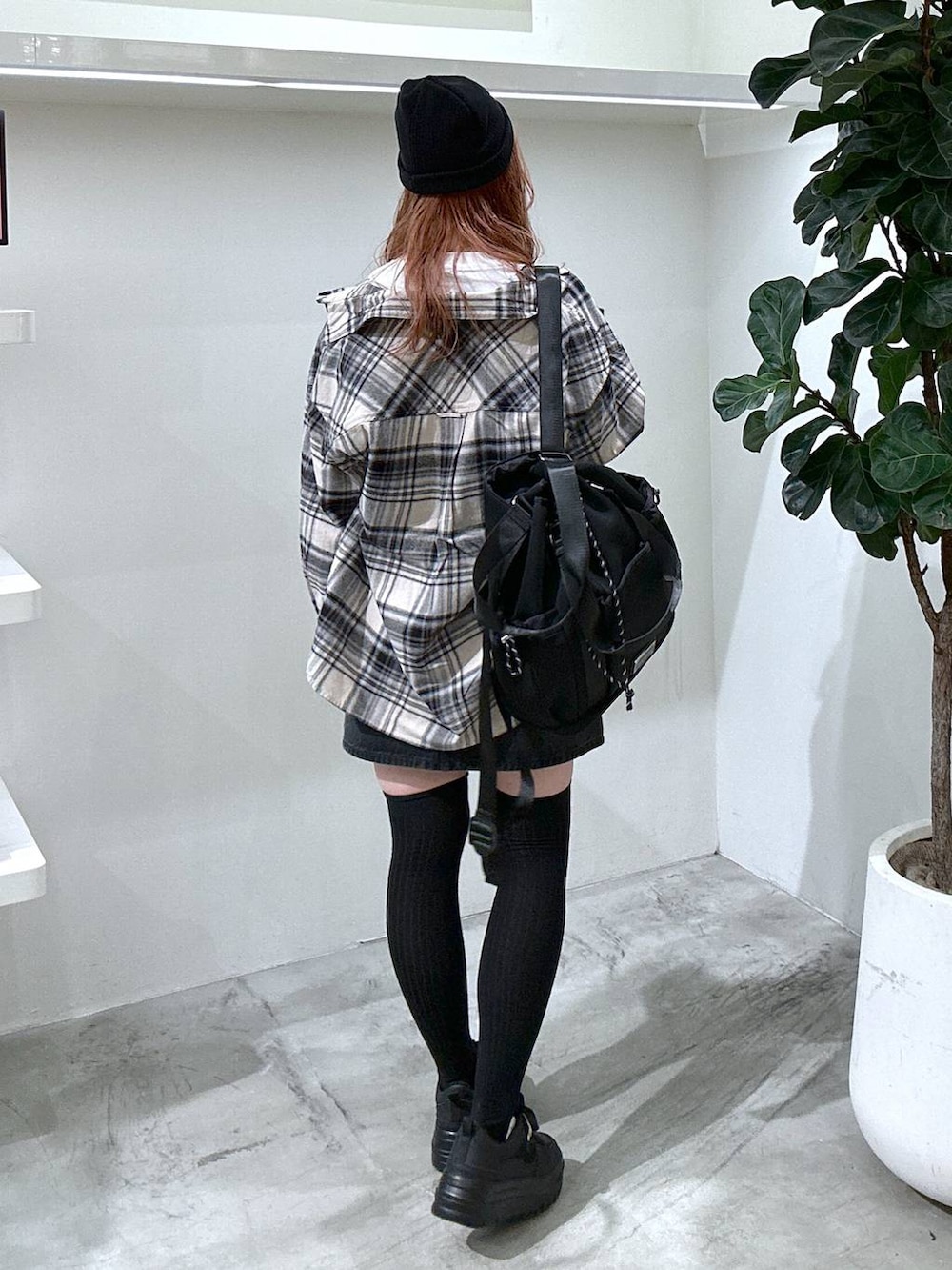 グレー系のスカート、ブラック系のバックパック/リュック、ホワイト系のTシャツ/カットソーを着用したレディースの秋コーディネートの3枚目の写真