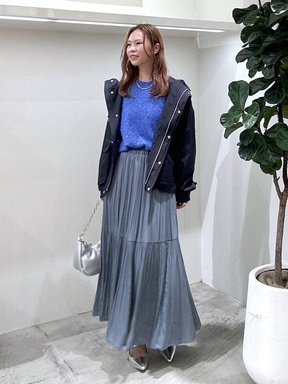 ブルー系のマウンテンパーカー、シルバー系のショルダーバッグ、ブルー系のスカートを着用したレディースの秋コーディネートの2枚目の写真