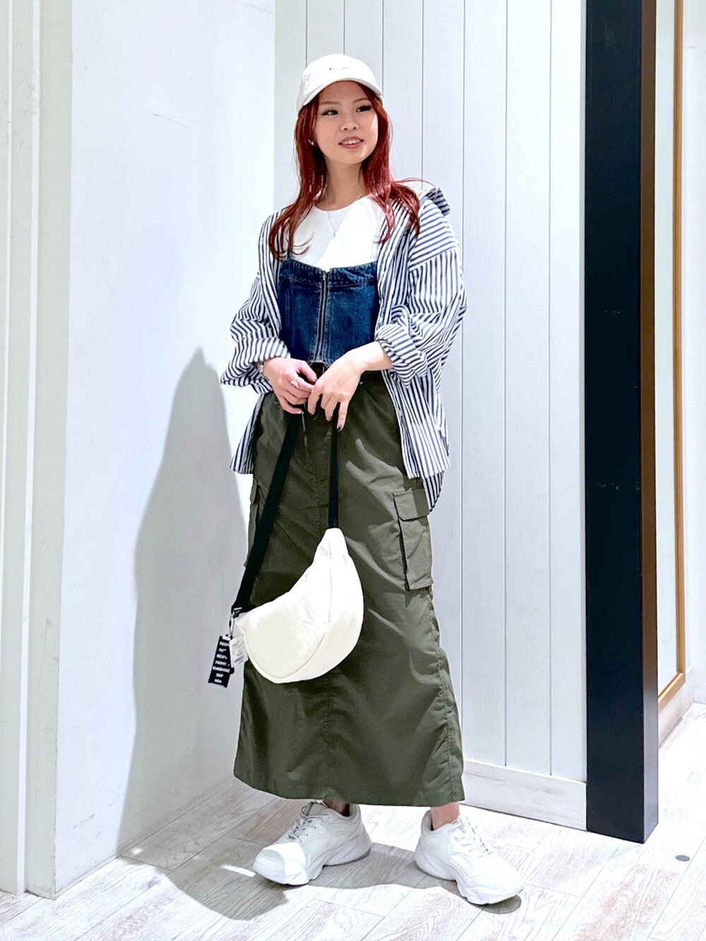 ホワイト系のスニーカー、グリーン系のスカート、ベージュ系のショルダーバッグを着用したレディースの春コーディネートの2枚目の写真