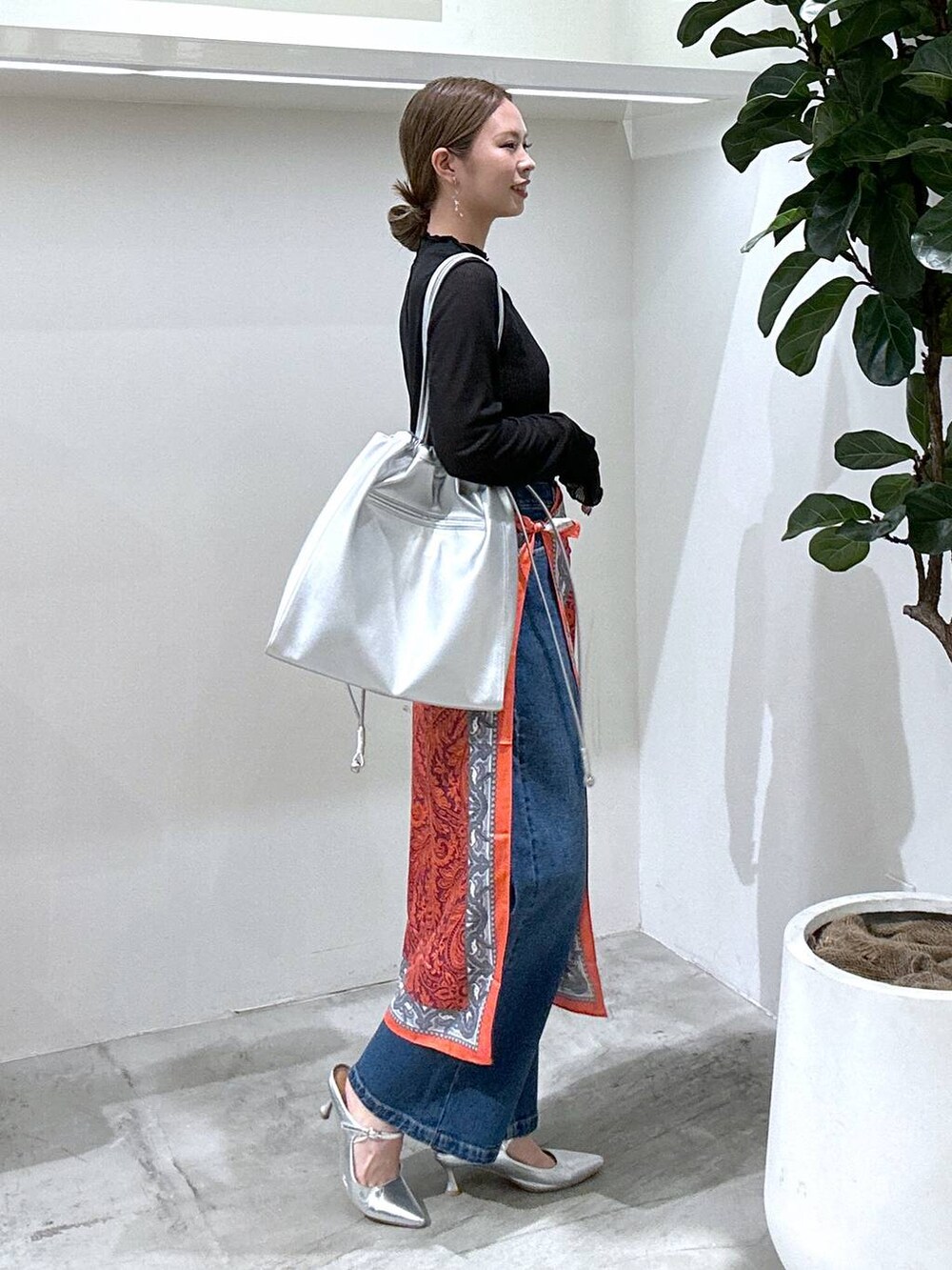 シルバー系のパンプス、ブラック系のTシャツ/カットソー、ブルー系のデニムパンツを着用したレディースの冬コーディネートの2枚目の写真