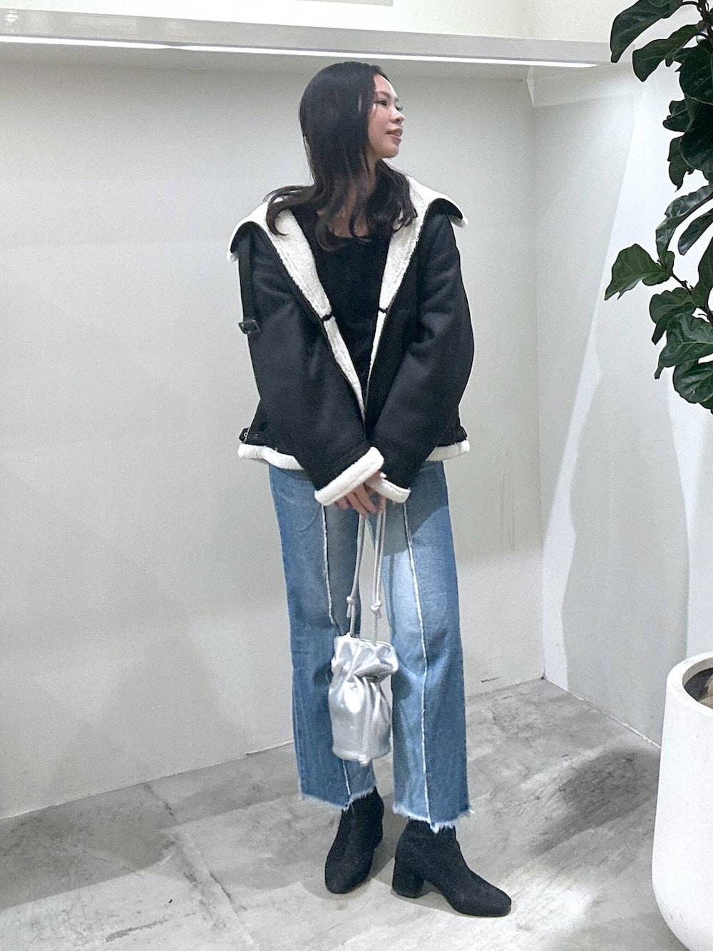 シルバー系のショルダーバッグ、ブラック系のTシャツ/カットソー、ブラック系のムートンコートを着用したレディースの冬コーディネートの2枚目の写真