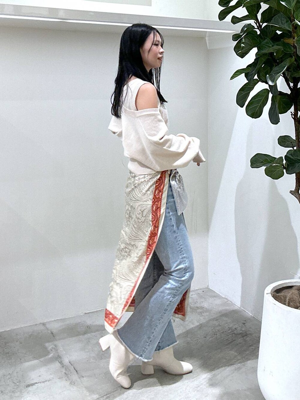 ブルー系のデニムパンツ、ベージュ系のブーツ、ホワイト系のニット/セーターを着用したレディースの冬コーディネートの3枚目の写真