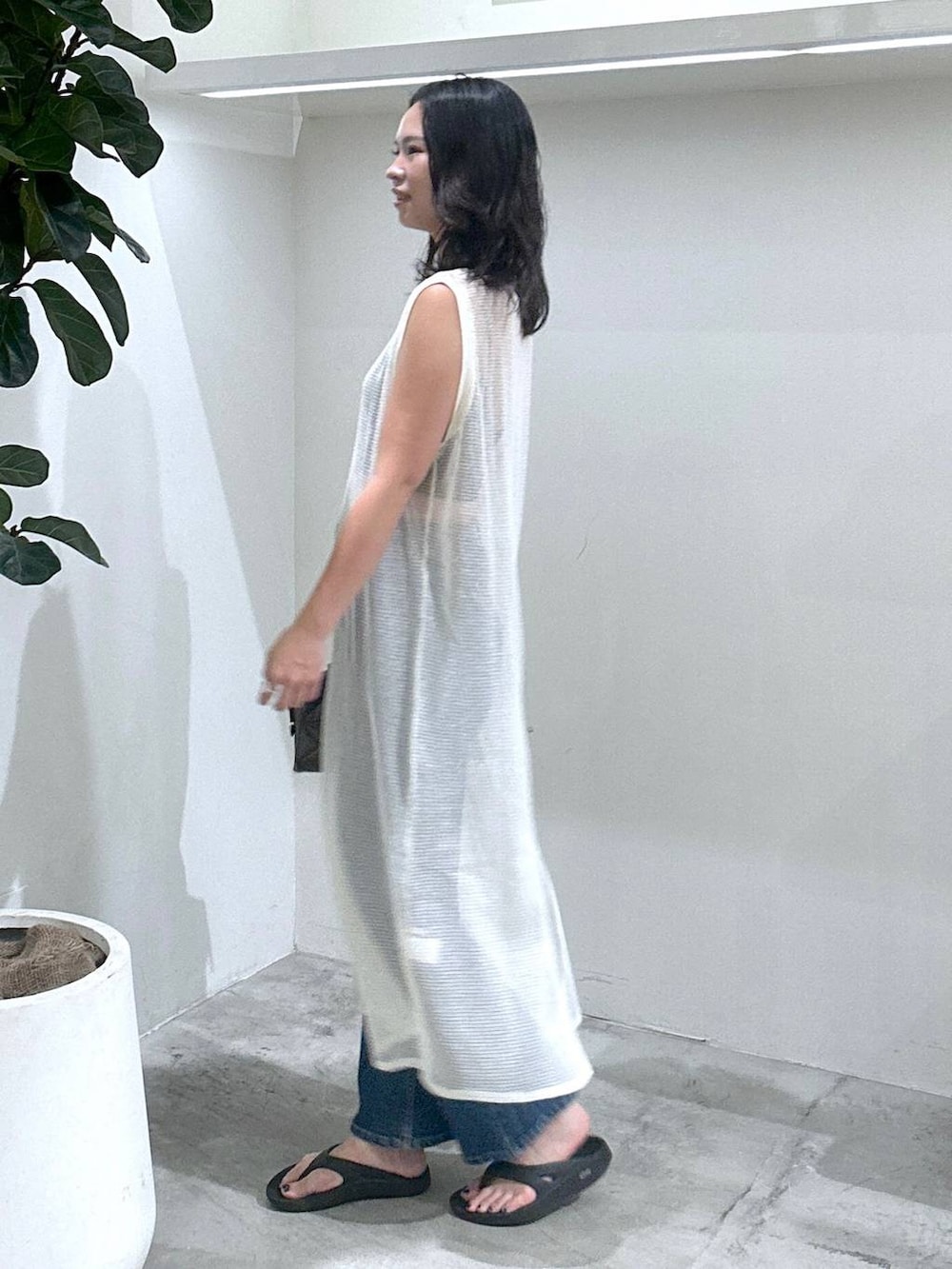 ブルー系のデニムパンツ、ホワイト系のワンピース、ブラック系のトートバッグを着用したレディースの夏コーディネートの2枚目の写真