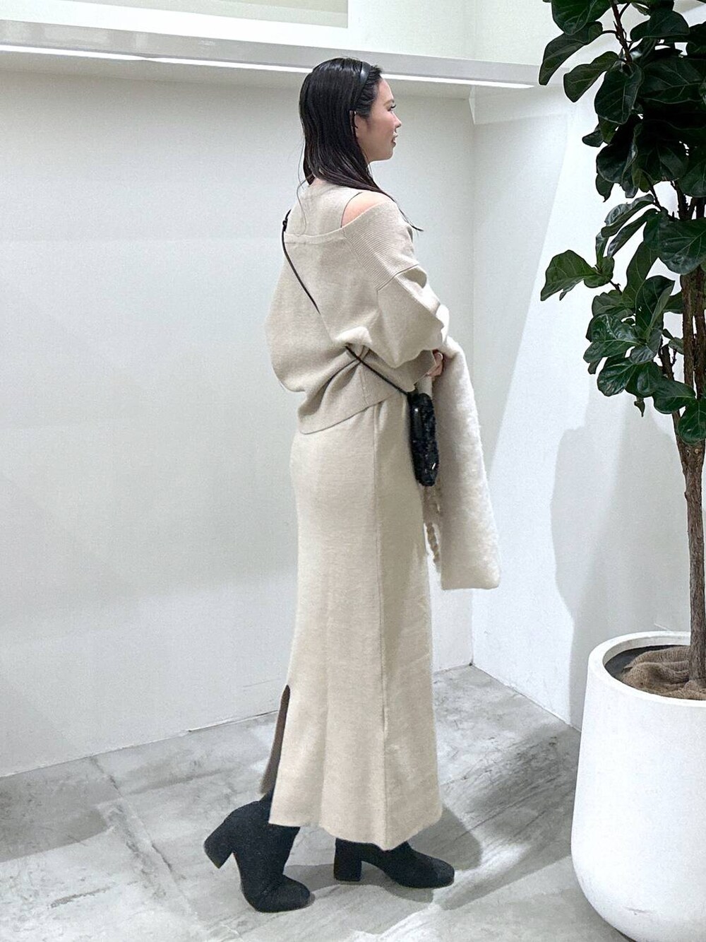 ブラック系のショルダーバッグ、ブラック系のブーツ、ブラウン系のワンピースを着用したレディースの冬コーディネートの3枚目の写真