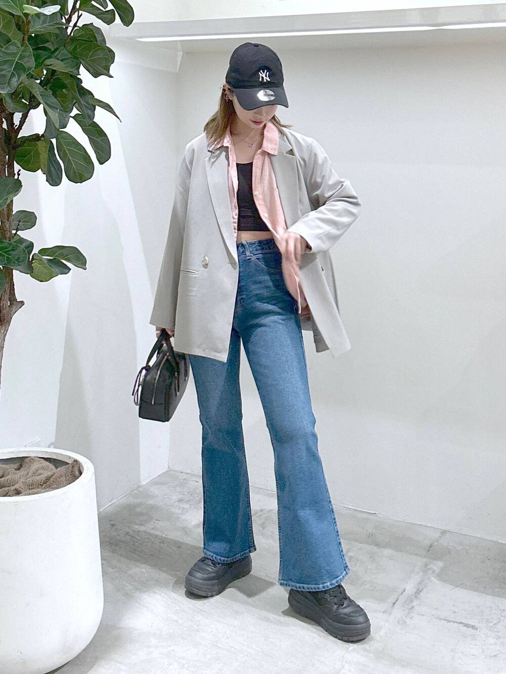 ブラック系のスニーカー、ピンク系のシャツ/ブラウス、ブラック系のショルダーバッグを着用したレディースの春コーディネートの2枚目の写真