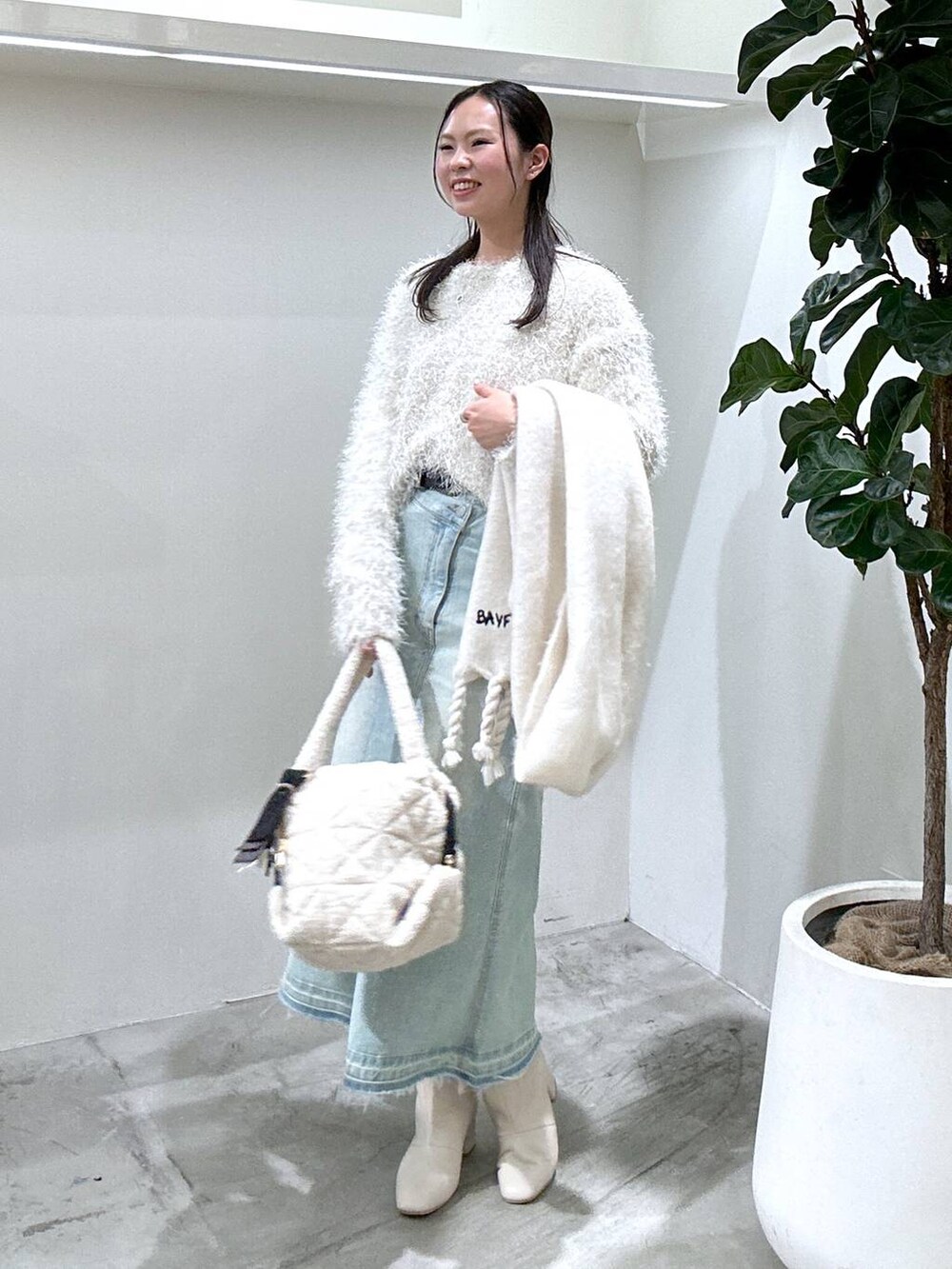 ブルー系のデニムスカート、ベージュ系のブーツ、ホワイト系のショルダーバッグを着用したレディースの冬コーディネートの2枚目の写真