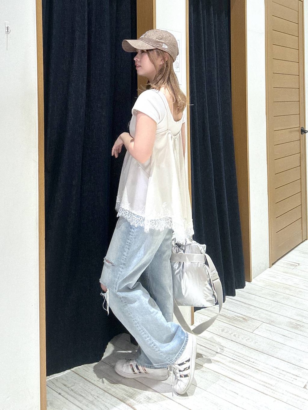 シルバー系のトートバッグ、ブルー系のデニムパンツ、ベージュ系のキャミソールを着用したレディースの春コーディネートの2枚目の写真