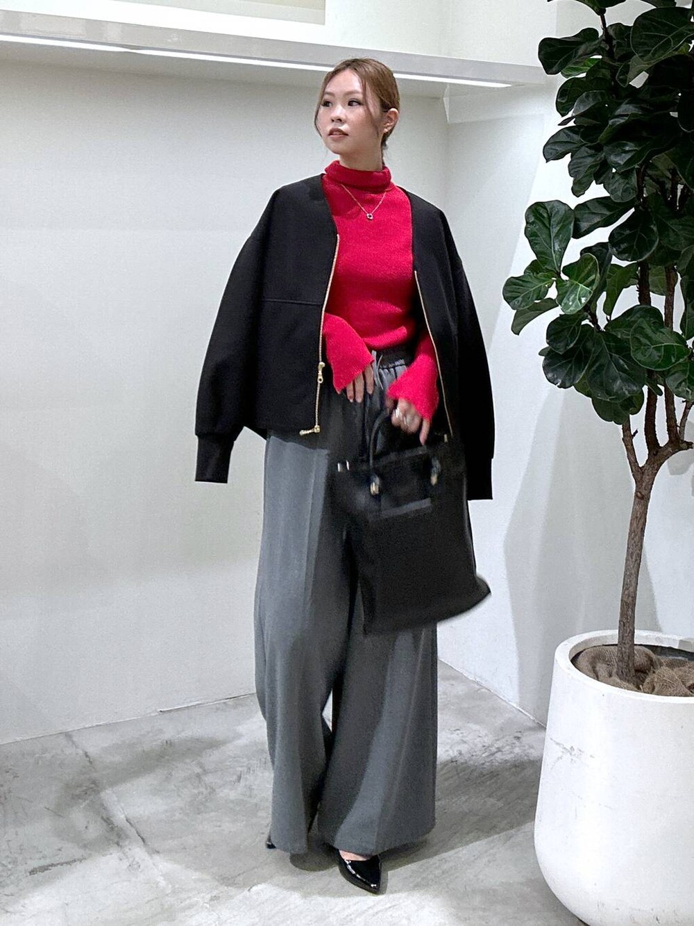 レッド系のニット/セーター、ブラック系のブルゾン、ブラック系のトートバッグを着用したレディースの秋コーディネートの2枚目の写真