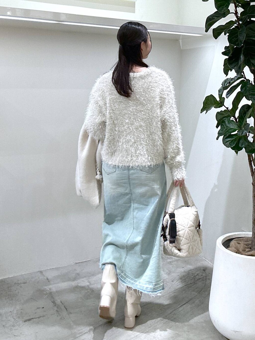 ブルー系のデニムスカート、ベージュ系のブーツ、ホワイト系のショルダーバッグを着用したレディースの冬コーディネートの4枚目の写真