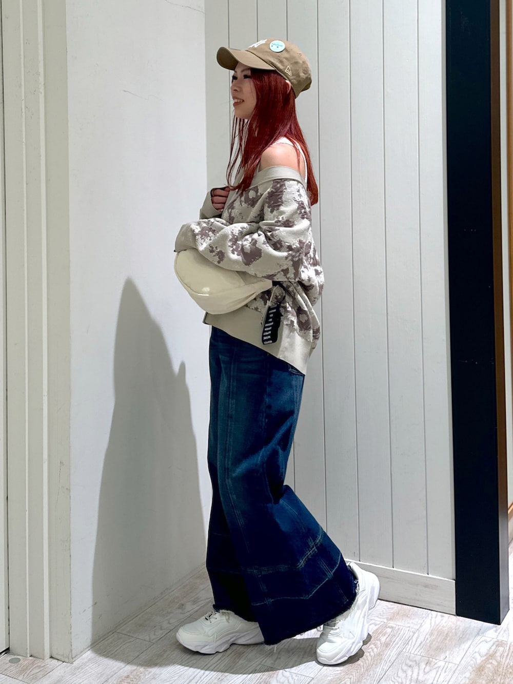 ホワイト系のスニーカー、ベージュ系のカーディガン/ボレロ、ブルー系のデニムパンツを着用したレディースの秋コーディネートの3枚目の写真