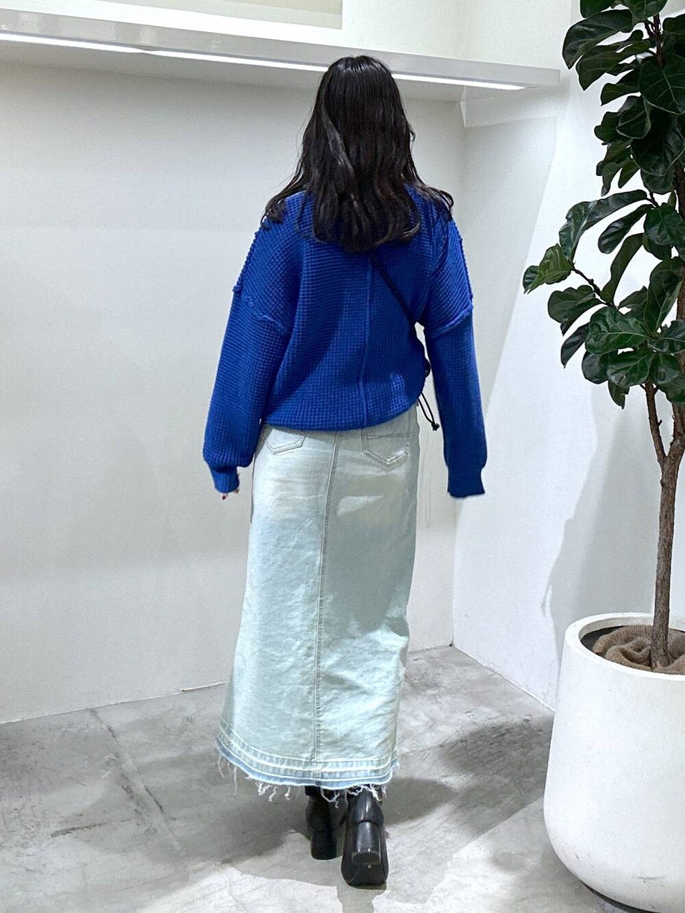 ブルー系のデニムスカート、ブラック系のショルダーバッグ、ブラック系のブーツを着用したレディースの冬コーディネートの4枚目の写真