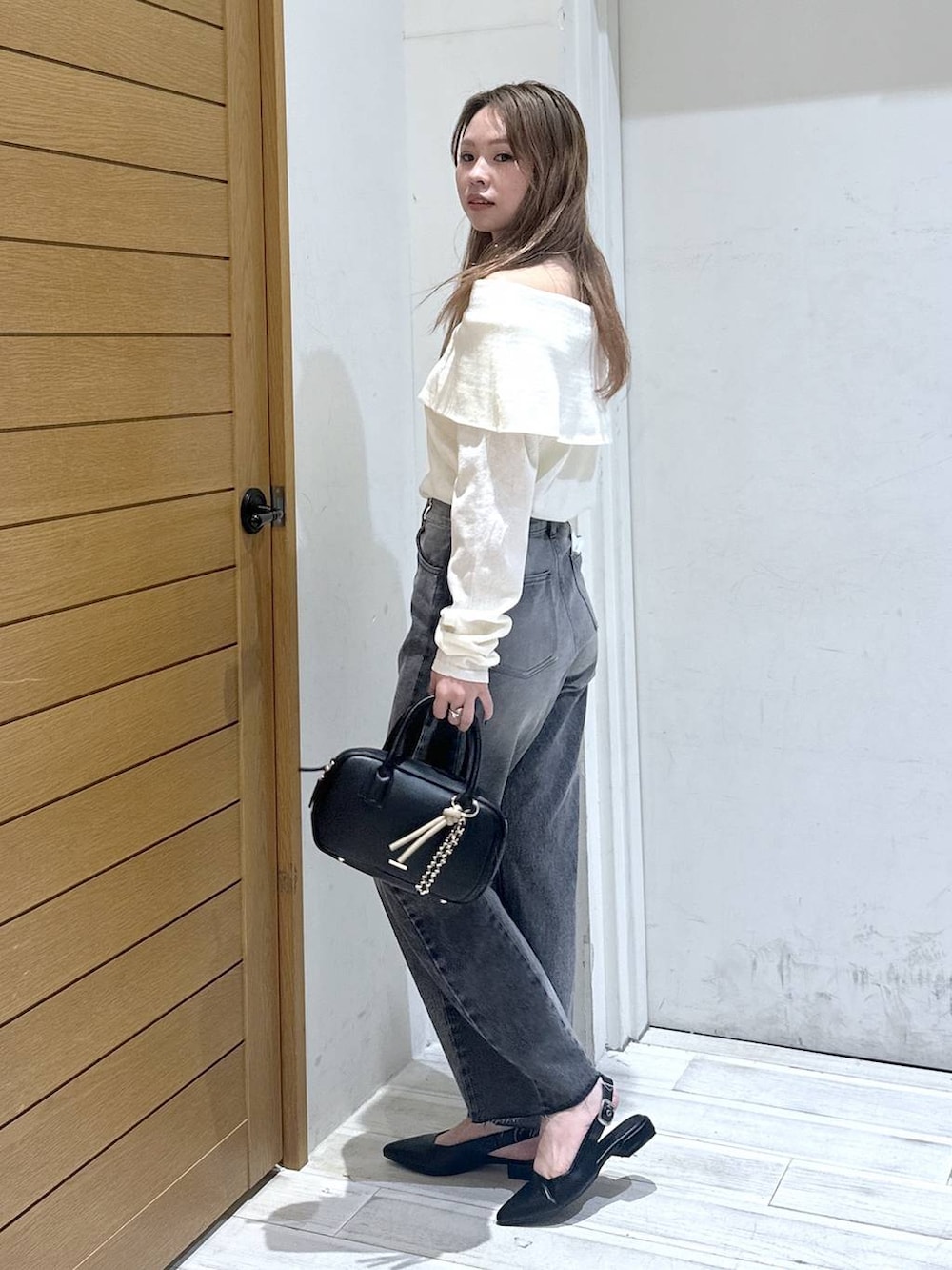 ブラック系のパンプス、ブラック系のデニムパンツ、ブラック系のハンドバッグを着用したレディースの春コーディネートの2枚目の写真