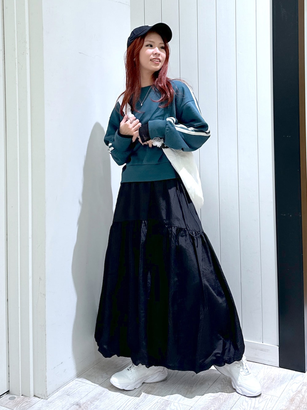 ブラック系のスカート、グリーン系のスウェット、ホワイト系のショルダーバッグを着用したレディースの春コーディネートの3枚目の写真