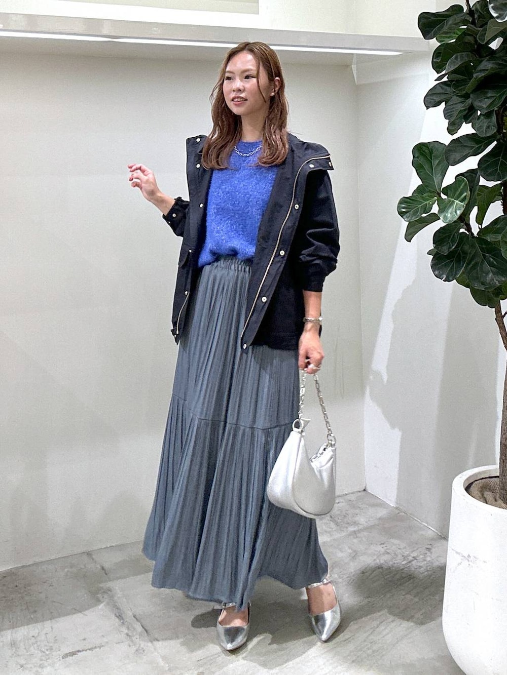 ブルー系のマウンテンパーカー、シルバー系のショルダーバッグ、ブルー系のスカートを着用したレディースの秋コーディネートの3枚目の写真