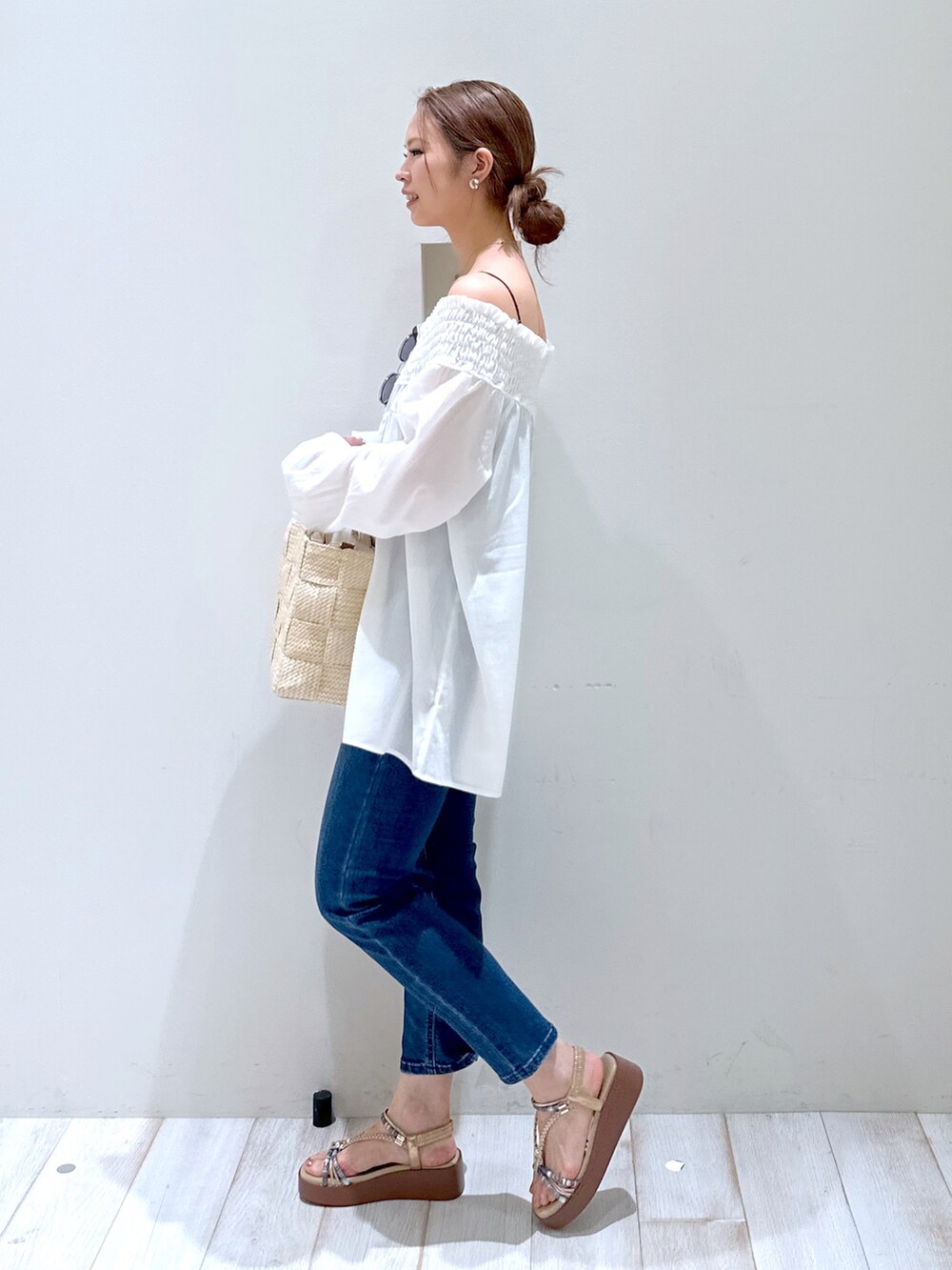 ブラウン系のトートバッグ、ベージュ系のサンダル、ブルー系のデニムパンツを着用したレディースの春コーディネートの3枚目の写真