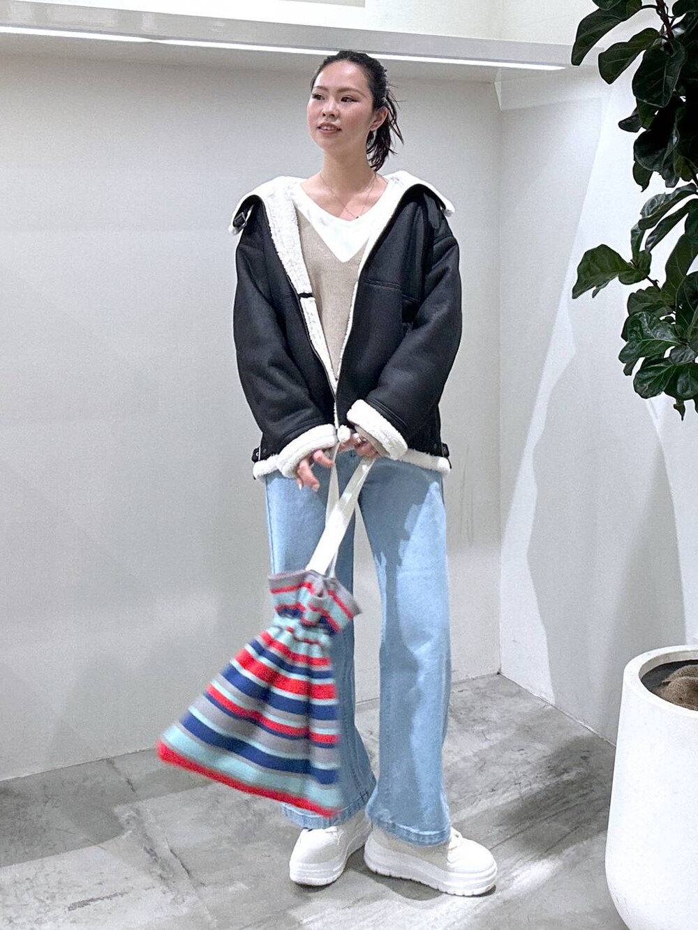 ホワイト系のスニーカー、ホワイト系のTシャツ/カットソー、ブラック系のムートンコートを着用したレディースの冬コーディネートの2枚目の写真