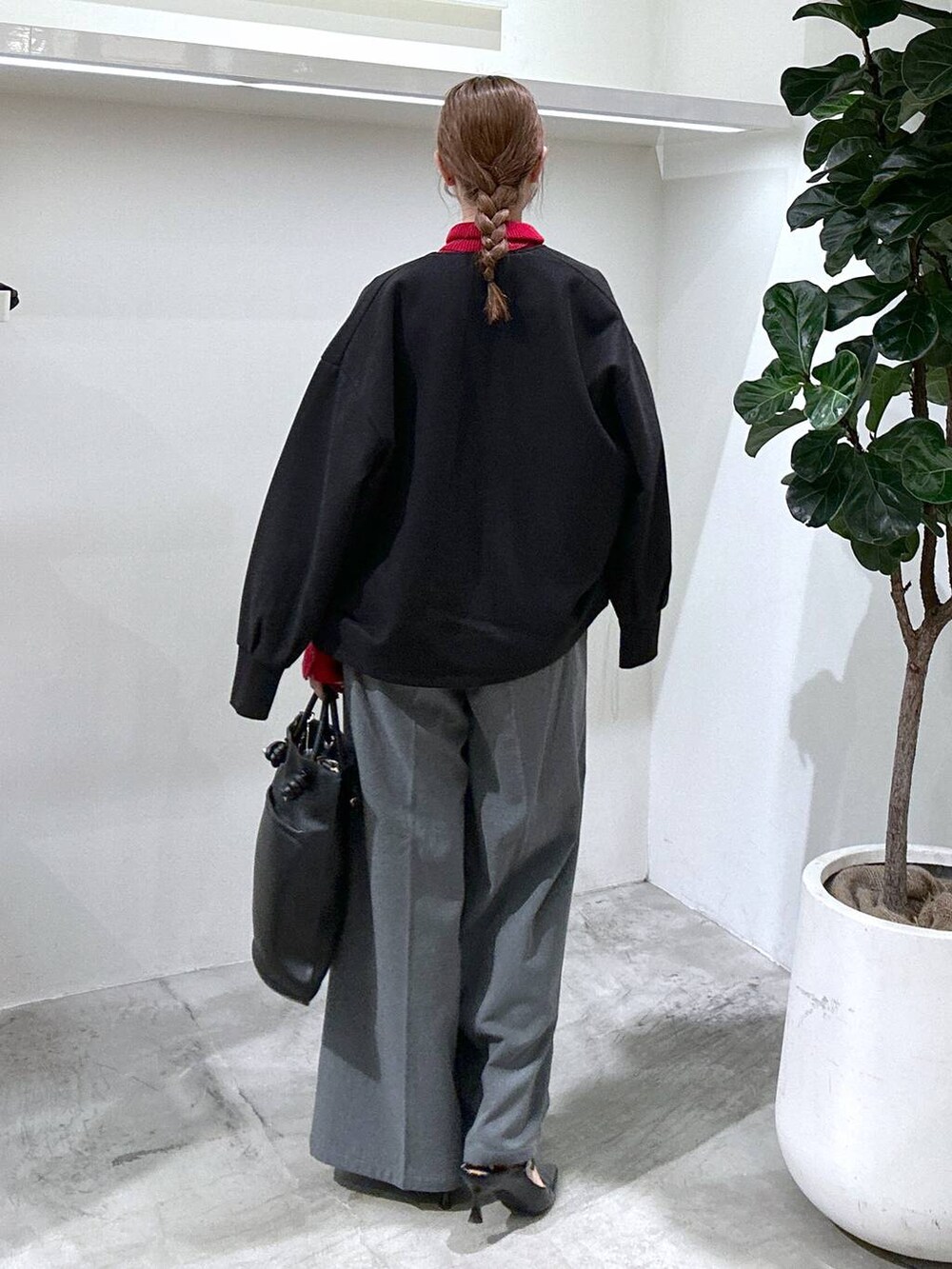 レッド系のニット/セーター、ブラック系のブルゾン、ブラック系のトートバッグを着用したレディースの秋コーディネートの4枚目の写真