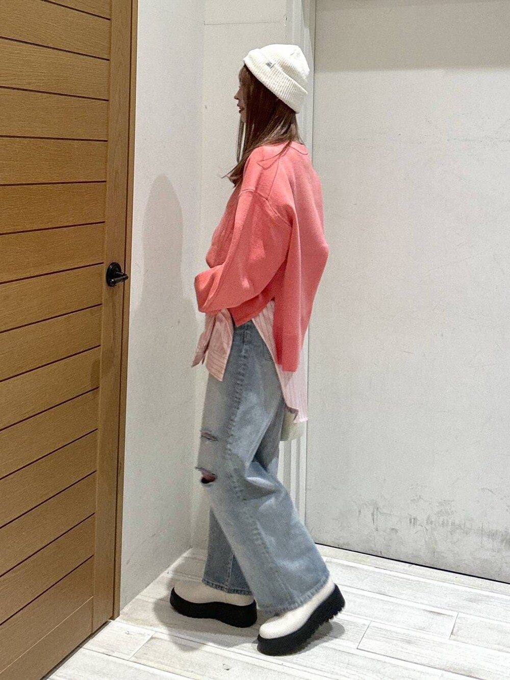 ベージュ系のブーツ、ブルー系のデニムパンツ、ホワイト系のハンドバッグを着用したレディースの春コーディネートの2枚目の写真