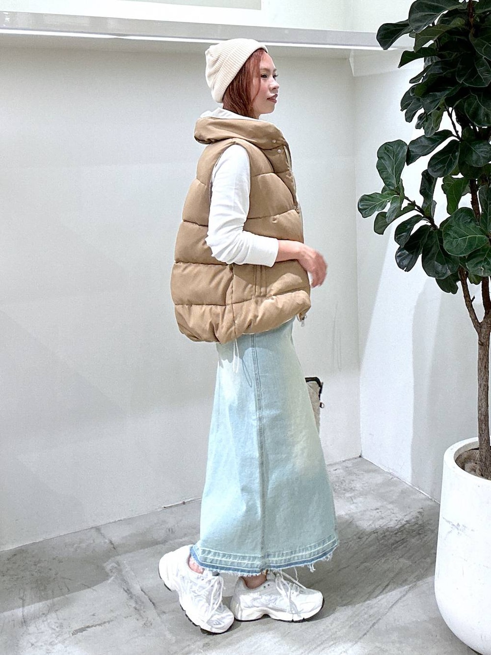 グレー系のスニーカー、ブルー系のデニムスカート、ブラウン系のベストを着用したレディースの秋コーディネートの3枚目の写真