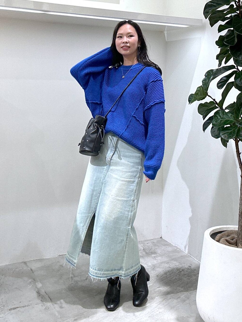 ブルー系のデニムスカート、ブラック系のショルダーバッグ、ブラック系のブーツを着用したレディースの冬コーディネートの2枚目の写真