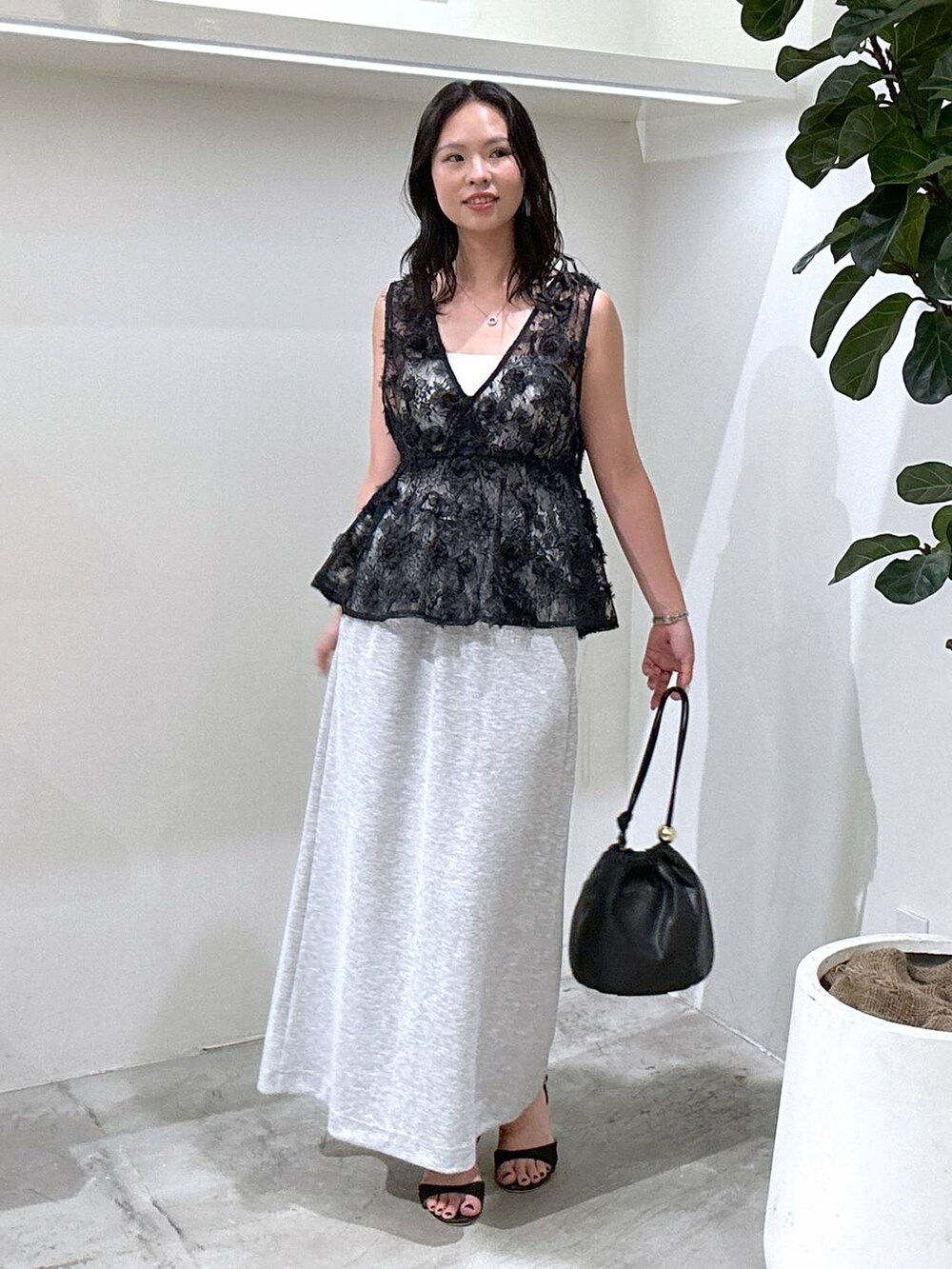 ブラック系のショルダーバッグ、ブラック系のサンダル、グレー系のスカートを着用したレディースの夏コーディネートの2枚目の写真