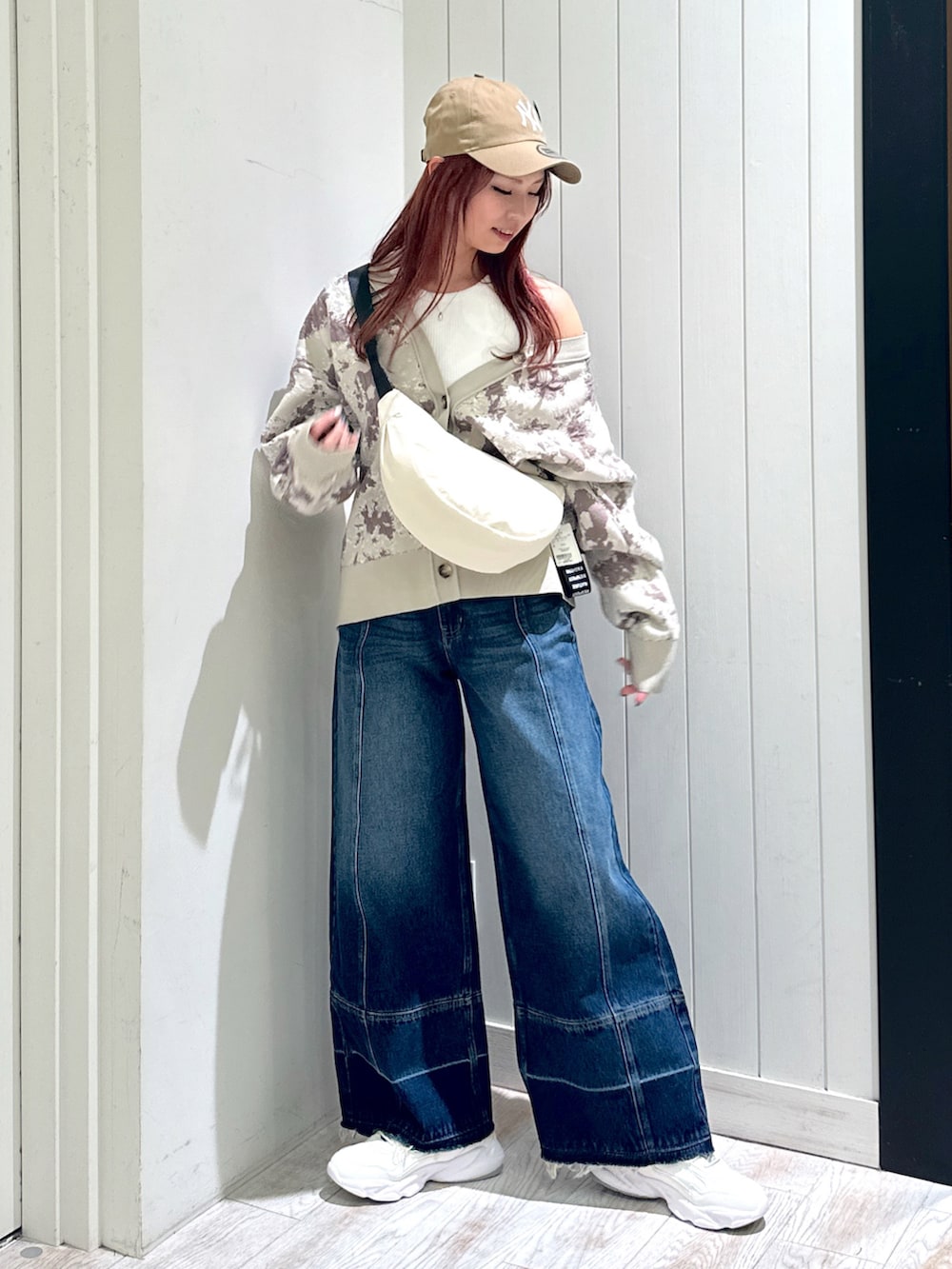 ホワイト系のスニーカー、ベージュ系のカーディガン/ボレロ、ブルー系のデニムパンツを着用したレディースの秋コーディネートの2枚目の写真